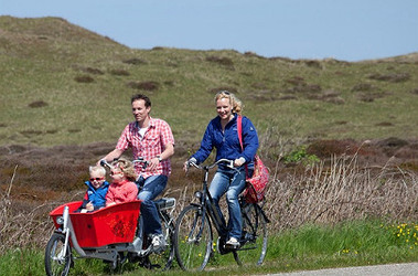 Man en vrouw aan het fietsen op Texel met kinderen in een bakfiets